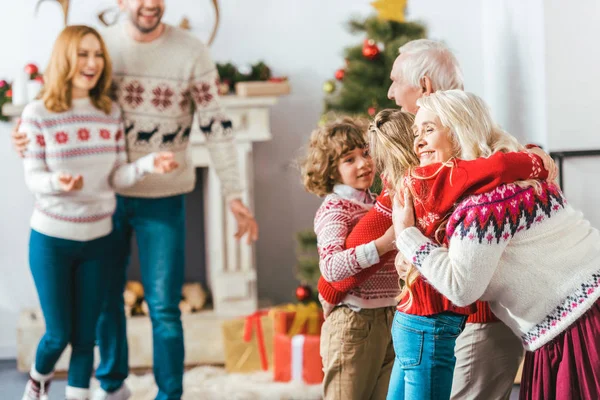 Nonni abbracciare con i bambini durante la vigilia di Natale a casa — Foto stock