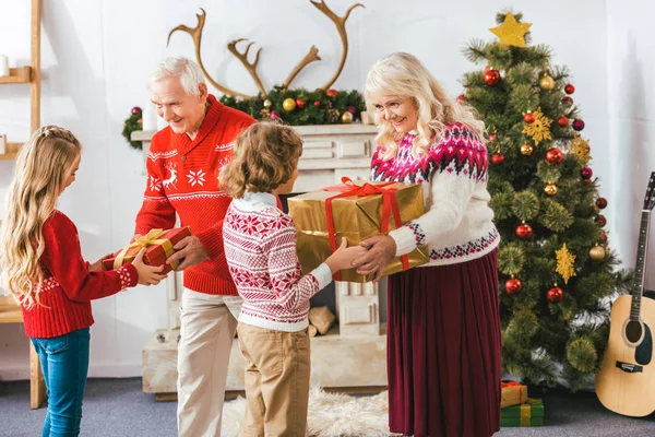 Grands-parents et donner des boîtes-cadeaux pour les enfants à Noël — Photo de stock