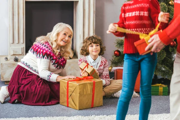 Happy senior woman sitting on floor with grandson during christmas eve — Stock Photo