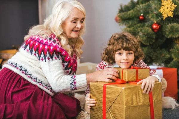 Happy grandmother and her grandson with christmas gifts looking at camera — Stock Photo