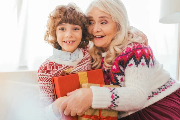 Grandmother embracing her grandson with christmas gifts — Stock Photo