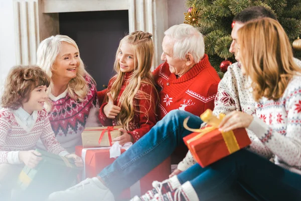 Heureux famille avec des boîtes-cadeaux assis sur le sol de la salle de séjour pendant Noël — Photo de stock