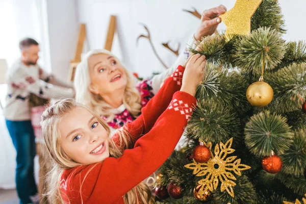 Abuela y nieta decorando el árbol de navidad juntos - foto de stock