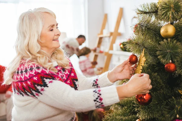 Feliz mujer mayor decorando árbol de Navidad - foto de stock