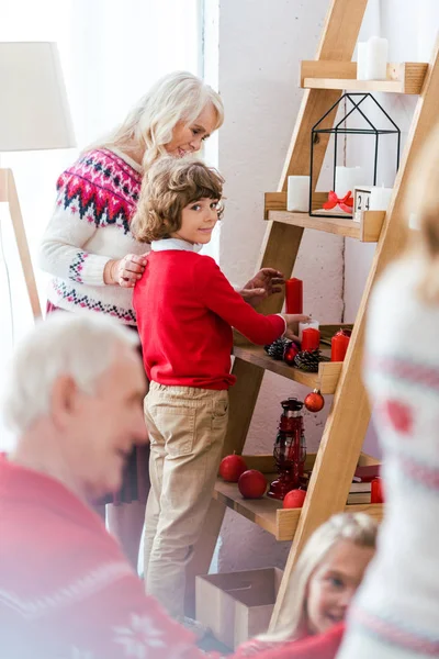 Adorable little kid decorating living room for christmas with his family — Stock Photo