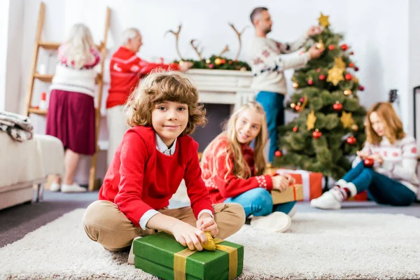 Souriant frères et sœurs assis sur le sol avec des cadeaux pendant la veille de Noël — Photo de stock