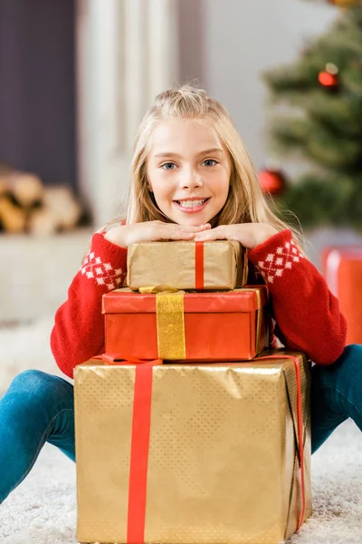 Adorable happy child leaning on stack of christmas gift boxes — Stock Photo