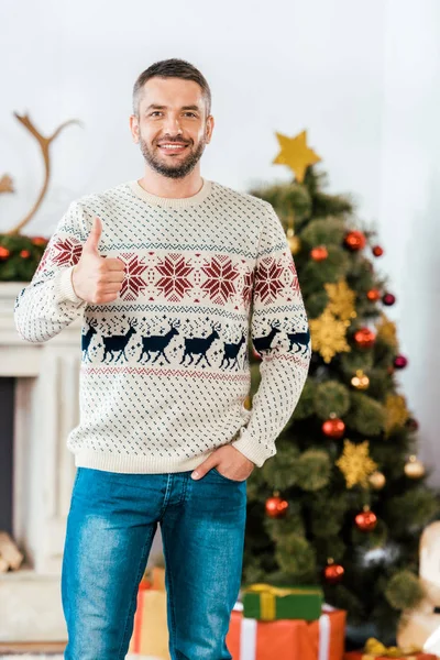 Bello uomo barbuto in maglione di Natale mostrando pollice in alto a macchina fotografica — Foto stock