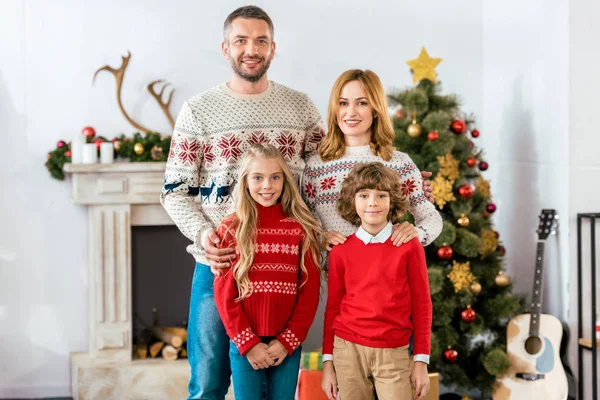 Feliz joven familia de pie juntos en Navidad y mirando a la cámara - foto de stock