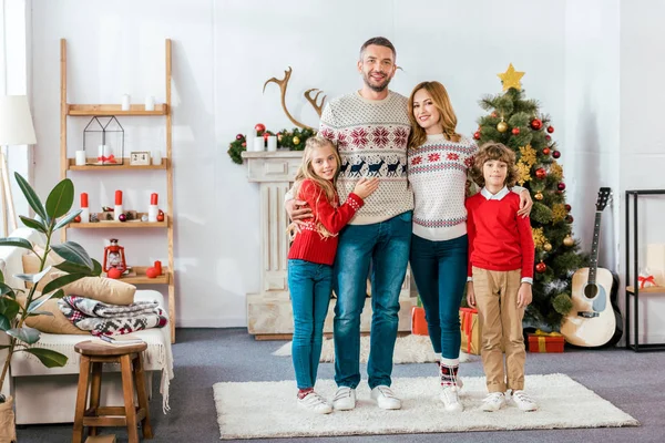 Happy young family embracing on christmas at home and looking at camera — Stock Photo