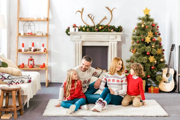 Padres e hijos sentados en el suelo juntos en Navidad en casa - foto de stock