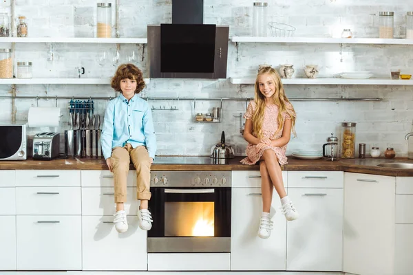 Geschwister sitzen am Küchentisch und schauen in die Kamera — Stockfoto