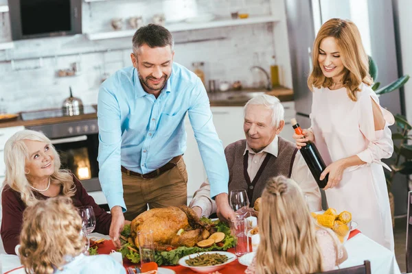 Família sorridente com peru celebrando dia de ação de graças em casa — Fotografia de Stock