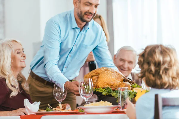 Handsome young man serving turkey on thanksgiving table — Stock Photo