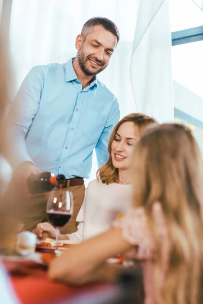 Hombre guapo sirviendo vino para su mujer durante la cena de vacaciones - foto de stock