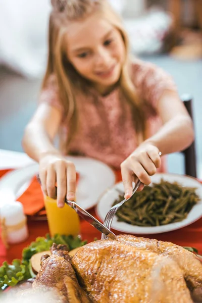 Adorable happy child cutting turkey on thanksgiving table — Stock Photo
