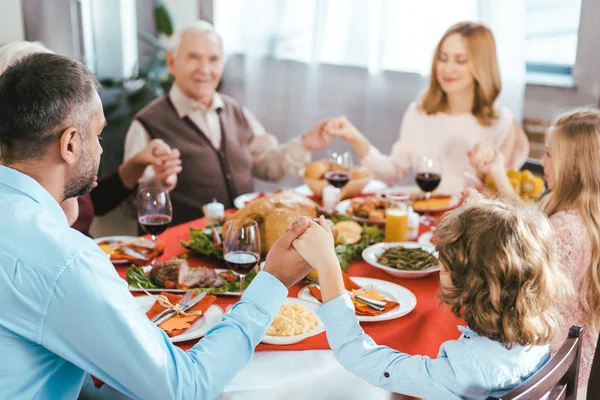 Счастливая семья молится перед праздничным ужином дома — стоковое фото