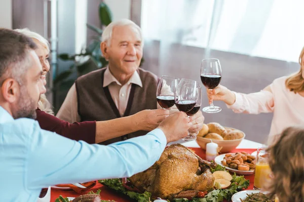 Hermosa familia feliz tintineo vasos de vino durante la cena de acción de gracias - foto de stock