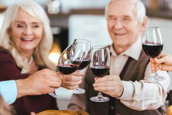 Senior couple clinking glasses with family during holiday celebration — Stock Photo