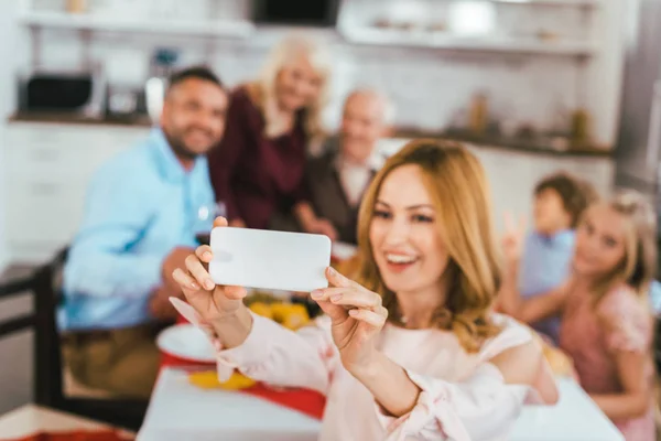 Jeune femme heureuse prenant selfie avec sa famille pendant le dîner de Thanksgiving — Photo de stock