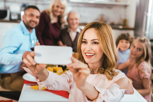 Jeune femme heureuse prenant selfie avec sa famille pendant le dîner de Thanksgiving — Photo de stock