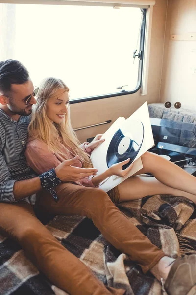 Hippie couple sitting inside campervan with vinyl records — Stock Photo