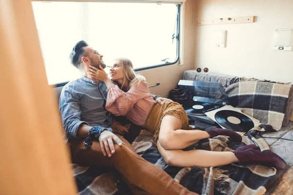 Smiling hippie couple listening music on vinyl player inside trailer — Stock Photo