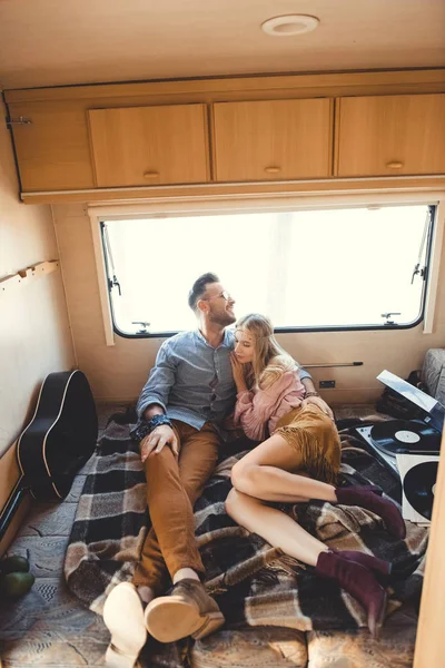 Beautiful couple hugging and resting inside campervan with acoustic guitar and vinyl records — Stock Photo