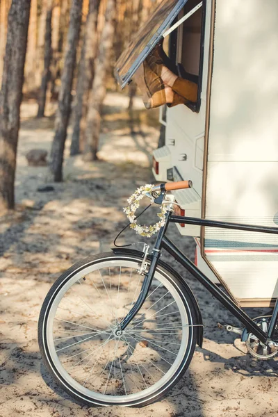 Male feet sticking out of the window of trailer while bicycle with wreath standing near campervan — Stock Photo