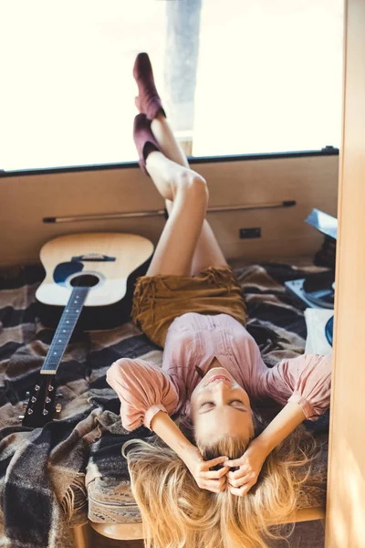 Хіпі дівчина розслабляється всередині трейлера з акустичною гітарою і вініловим плеєром — стокове фото