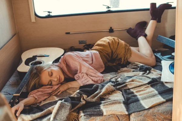 Hippie girl sleeping inside trailer with acoustic guitar, vinyl player and records — Stock Photo