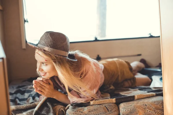 Beautiful hippie girl in hat lying inside camper van — Stock Photo