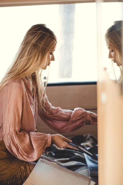Blonde hippie girl putting vinyl record into player inside camper van — Stock Photo