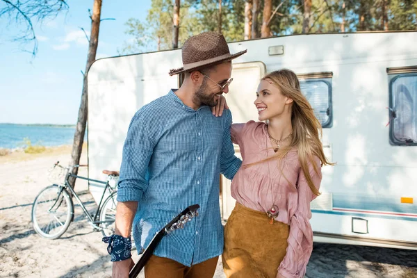 Young hippie couple hugging and walking near trailer — Stock Photo