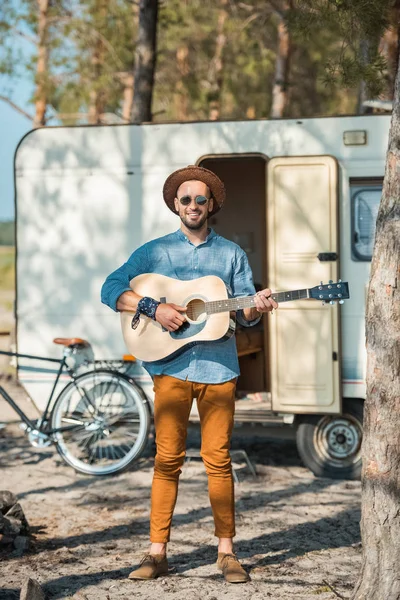 Guitarrista masculino tocando na guitarra acústica perto de campervan com bicicleta — Fotografia de Stock