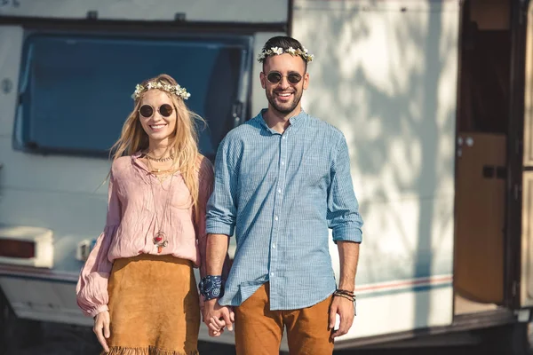 Hippie couple holding hands and posing near trailer — Stock Photo
