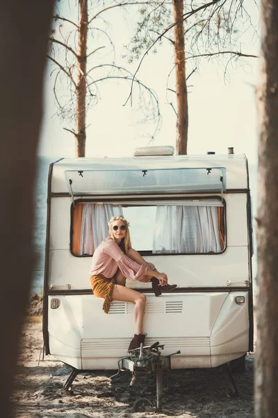 Junge Hippie-Frau mit Kranz und Sonnenbrille sitzt auf Anhänger — Stockfoto