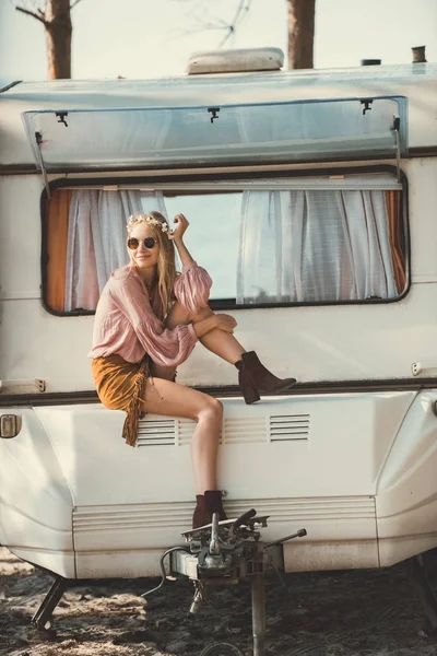 Hippie ragazza in ghirlanda e occhiali da sole seduto sul camper — Foto stock