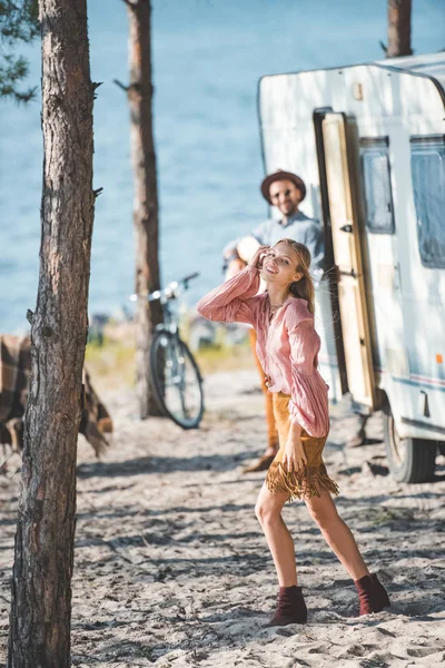 Menina feliz atraente dançando enquanto o homem tocando guitarra perto de campervan — Fotografia de Stock