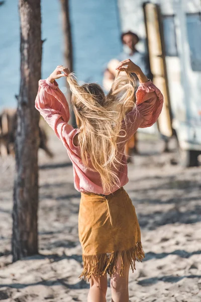 Vista trasera de chica hippie bailando mientras el hombre tocando la guitarra cerca del remolque - foto de stock
