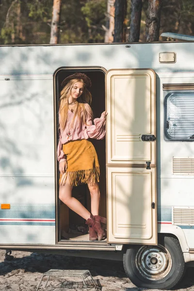 Attractive hippie girl in hat posing in door of camper van — Stock Photo