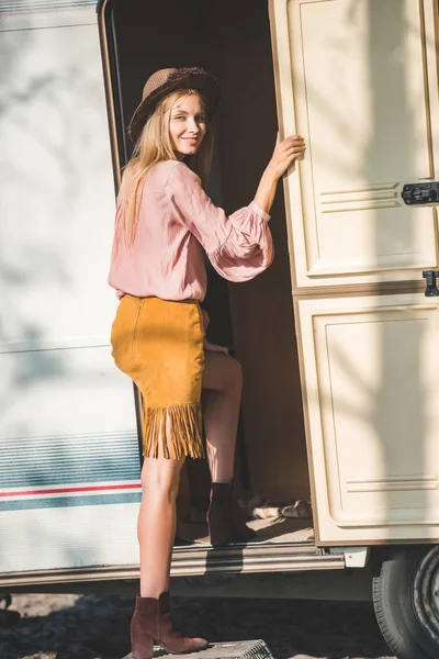 Beautiful hippie girl in hat coming into campervan — Stock Photo