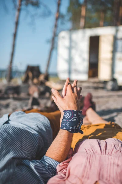 Cropped view of couple holding hands and relaxing near trailer — Stock Photo
