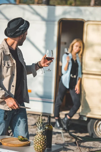 Selective focus of man with glass of wine looking at girlfriend near campervan — Stock Photo