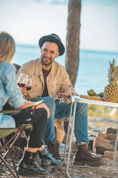 Giovane coppia con bicchieri di vino parlando durante un picnic — Foto stock