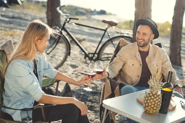 Giovane bella coppia clinking con bicchieri di vino durante un picnic, bicicletta su sfondo — Foto stock