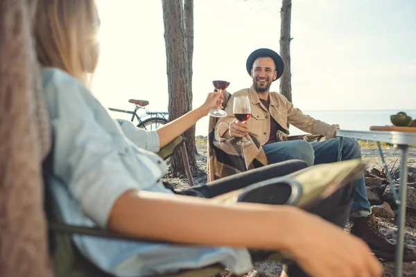 Jeune couple cliquetis avec des verres de vin pendant le pique-nique — Photo de stock