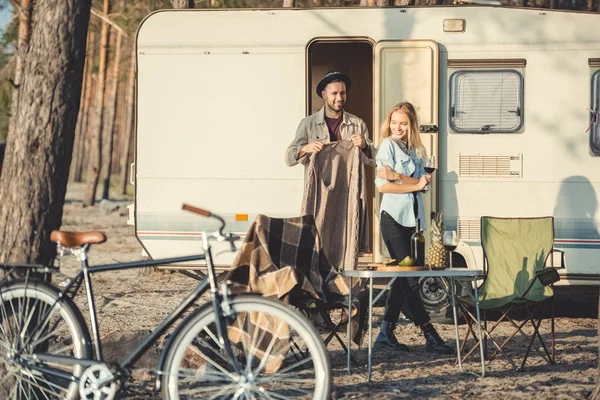 Jovem vestindo camisola quente em sua namorada perto de campervan, bicicleta em primeiro plano — Fotografia de Stock