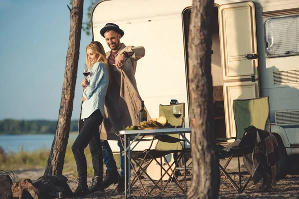 Man wearing warm sweater on his girlfriend near campervan — Stock Photo