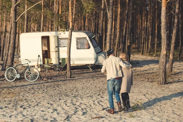 Vue arrière de couple étreignant et allant à la remorque dans le camp forestier avec vélo — Photo de stock